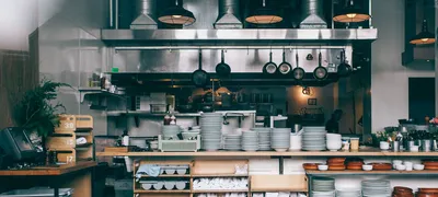 Cluttered open-kitchen restaurant with stacked plates and boxes