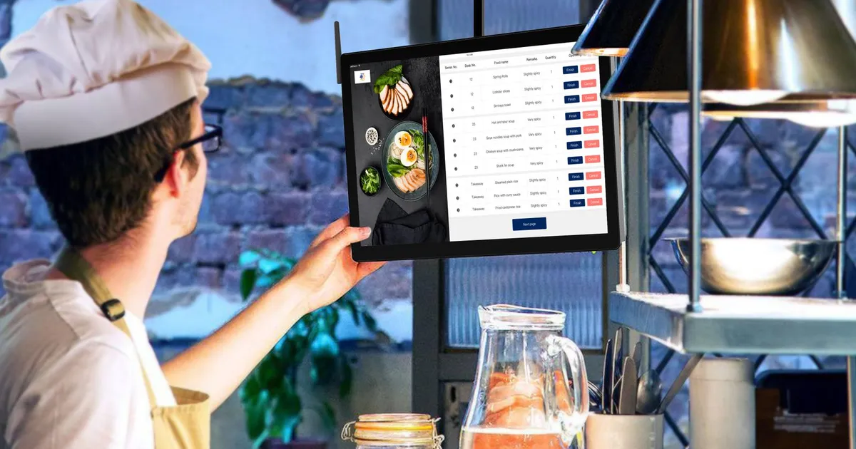 Chef in a commercial kitchen holding a tablet showing a digital checklist