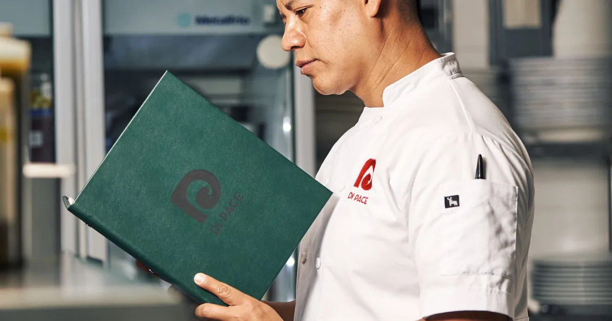 Chef reviewing a document closely in a commercial kitchen